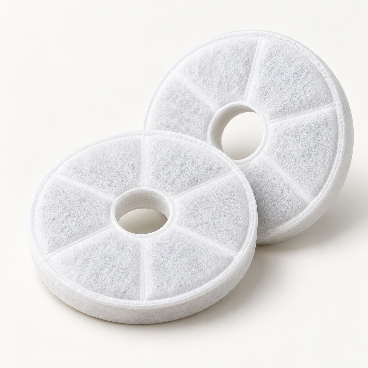 Two white circular fountain filter pads photographed together on an off-white studio background.